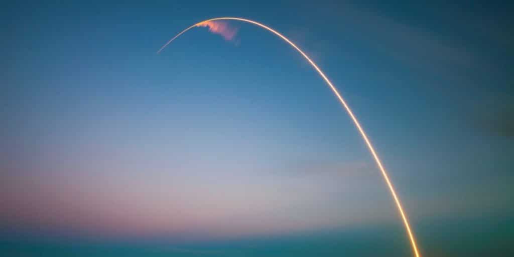 A rocket is launching into a vibrant sunset sky - a metaphor for startup growth and new beginnings.