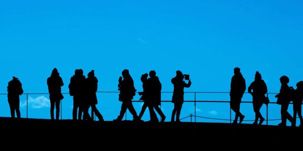 An image shows people with different buyer personas standing on a bridge while admiring the view and taking photos.
