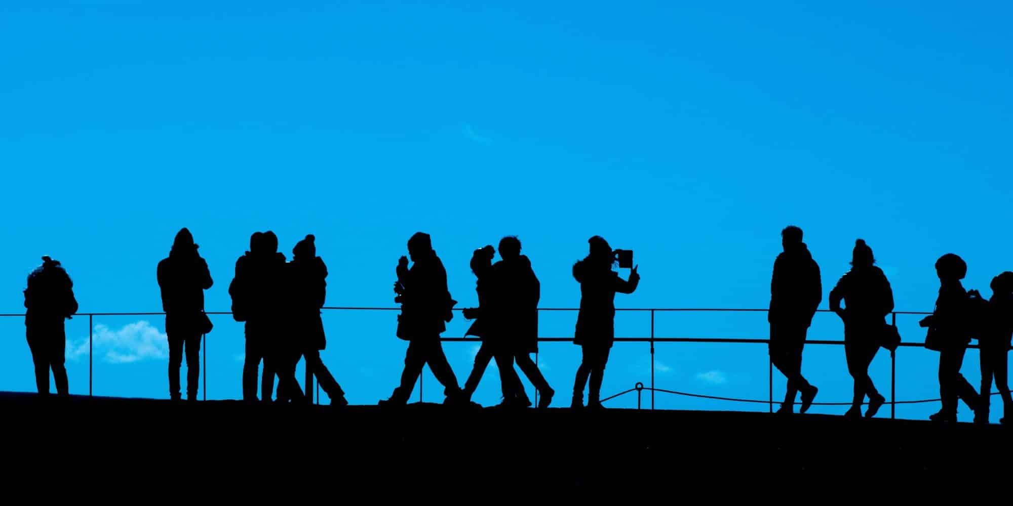 An image shows people with different buyer personas standing on a bridge while admiring the view and taking photos.