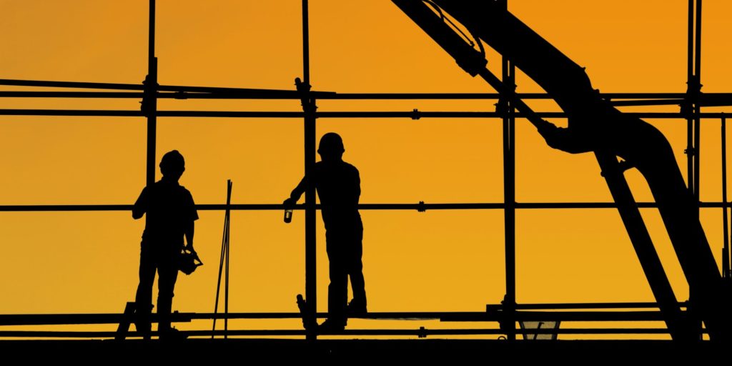 A black and yellow image of construction workers on a building site represents how long it takes to build a team.
