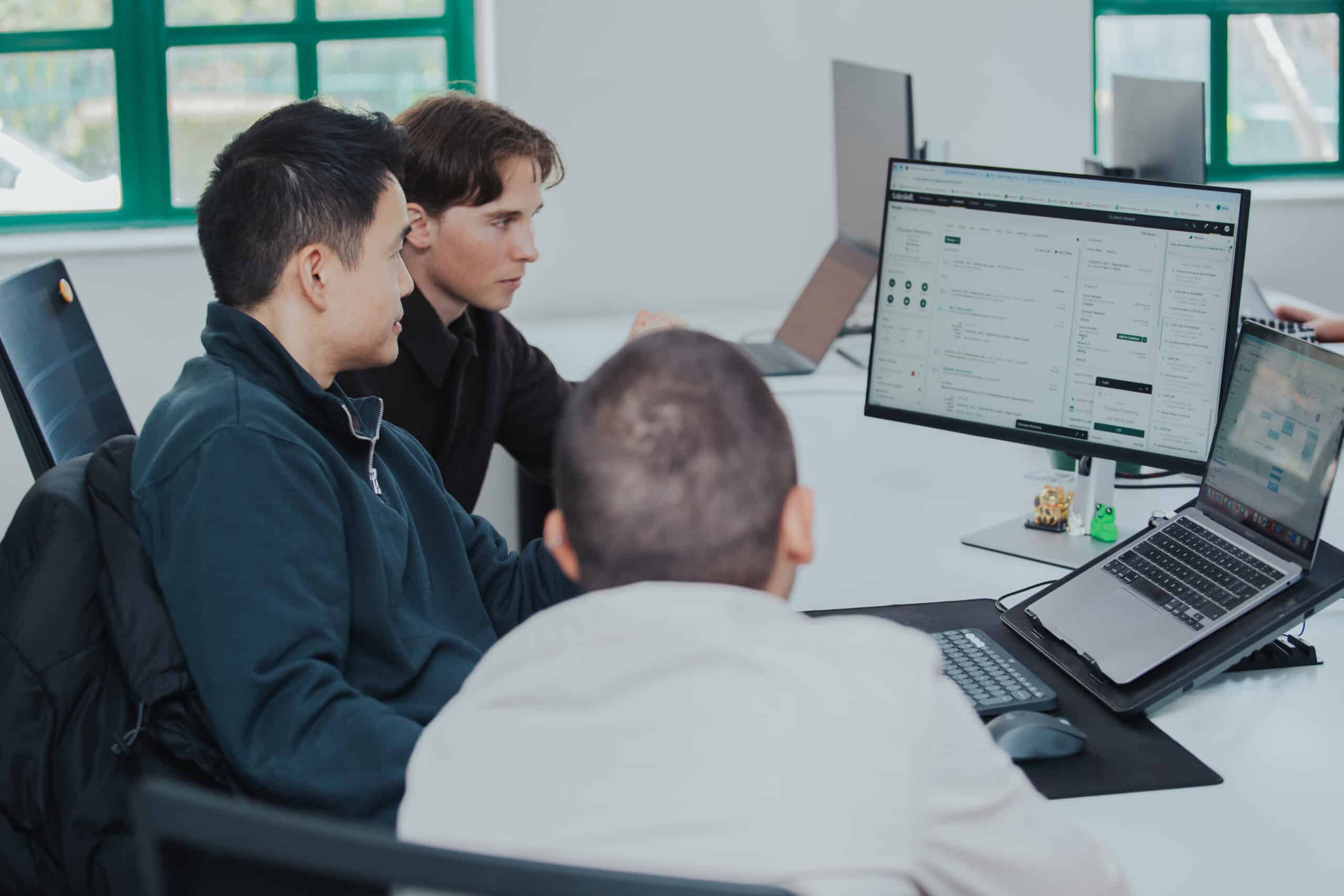 Delta-v SDR team reviewing sales pipeline activity on a Salesloft dashboard in the office.